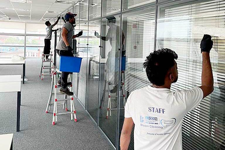 Addetti di una impresa di pulizie che puliscono la vetrata di un ufficio a Milano