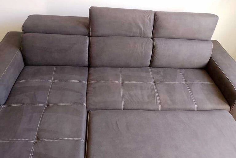 Un divano componibile grigio con cuciture a vista su una parete bianca semplice, ideale per chi cerca lavaggio divani a domicilio Milano sud-ovest per mantenere il suo aspetto immacolato.