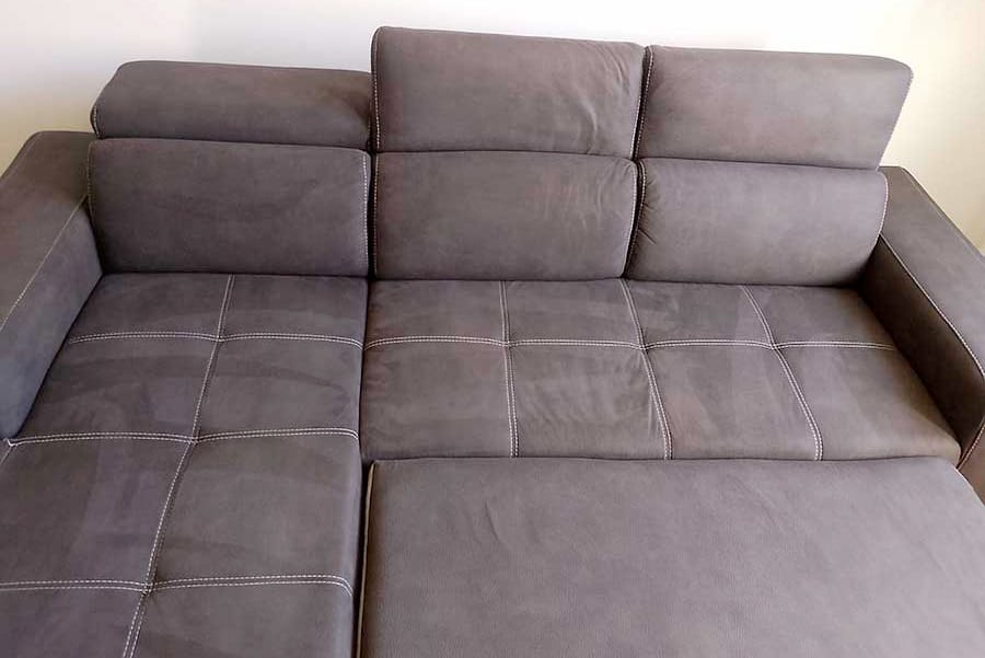 Un divano componibile grigio con cuciture a vista su una parete bianca semplice, ideale per chi cerca lavaggio divani a domicilio Milano sud-ovest per mantenere il suo aspetto immacolato.