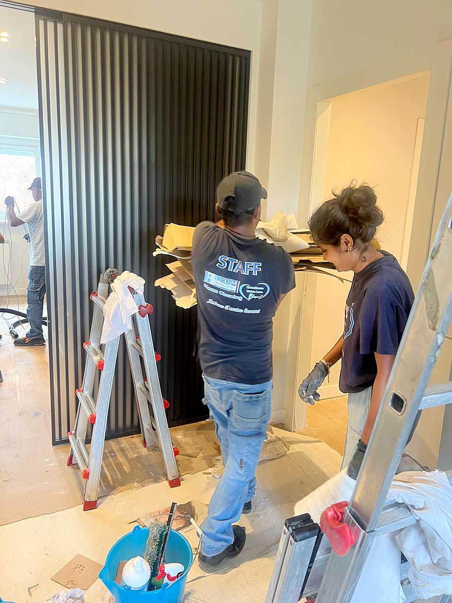 Due operai rimuovono i detriti da una stanza in ristrutturazione in Zona Moscova, a Milano; nelle vicinanze sono visibili attrezzi e una scala, a sottolineare l'accurato servizio di Pulizia Appartamenti.